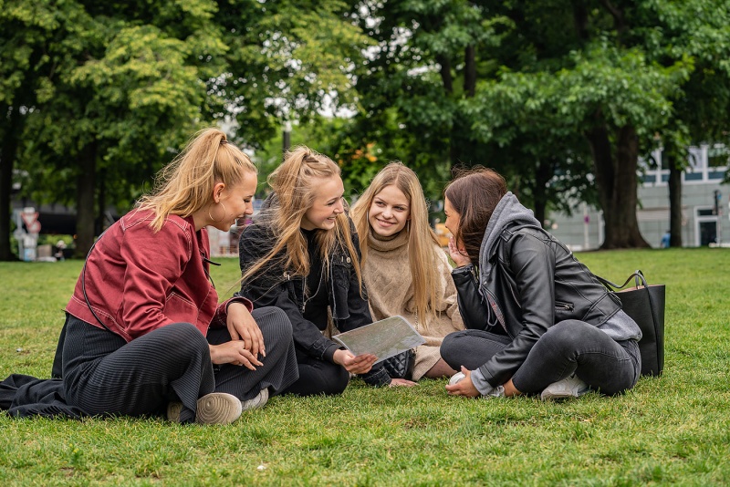 Schüler*innen sitzen auf einer Wiese auf der Museumsinsel in Berlin.