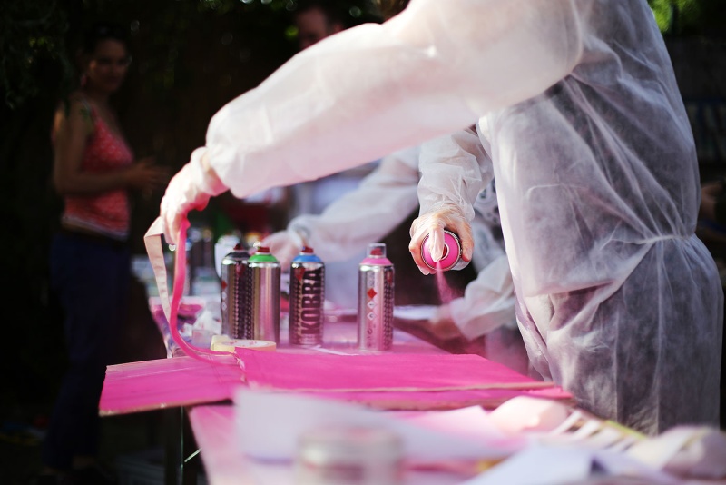 Mit einer pink-farbenden Sprühdose wird auf dem Graffiti-Workshop der Berlinpiloten auf Karton gesprüht. 